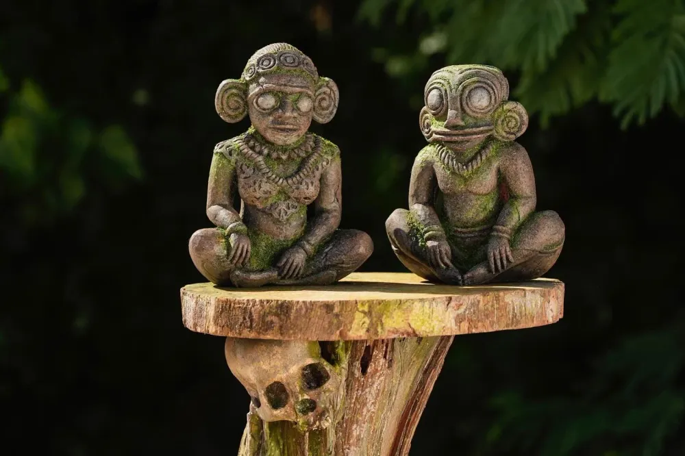 Two carved Survivor 47 hidden immunity idols on a wooden stand in the jungle