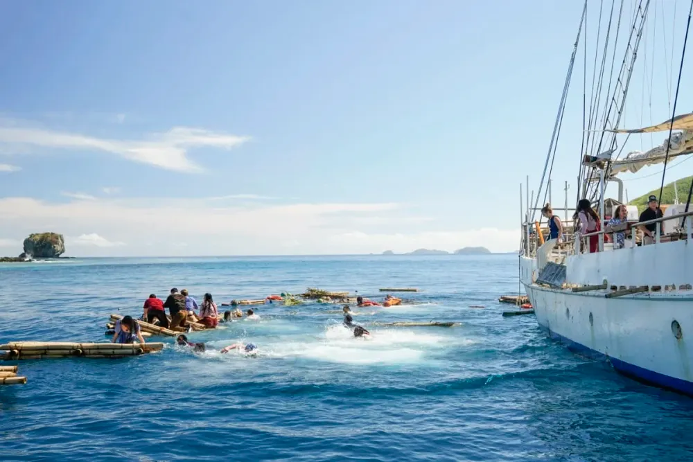 Survivor 51 castaways on rafts beside the boat that brought them to Fiji