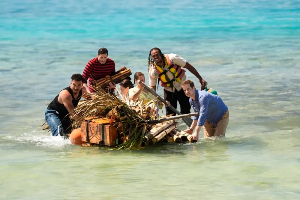 Survivor 51 castaways hauling a raft through shallow water