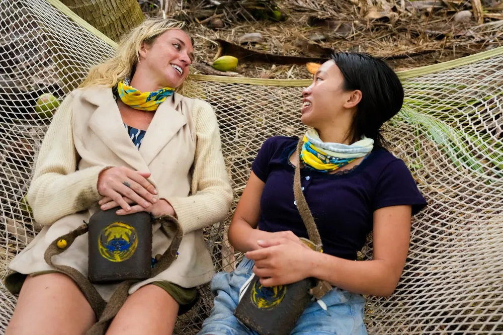 Two Survivor 51 castaways laughing together in a hammock at the Toka camp in Episode 3